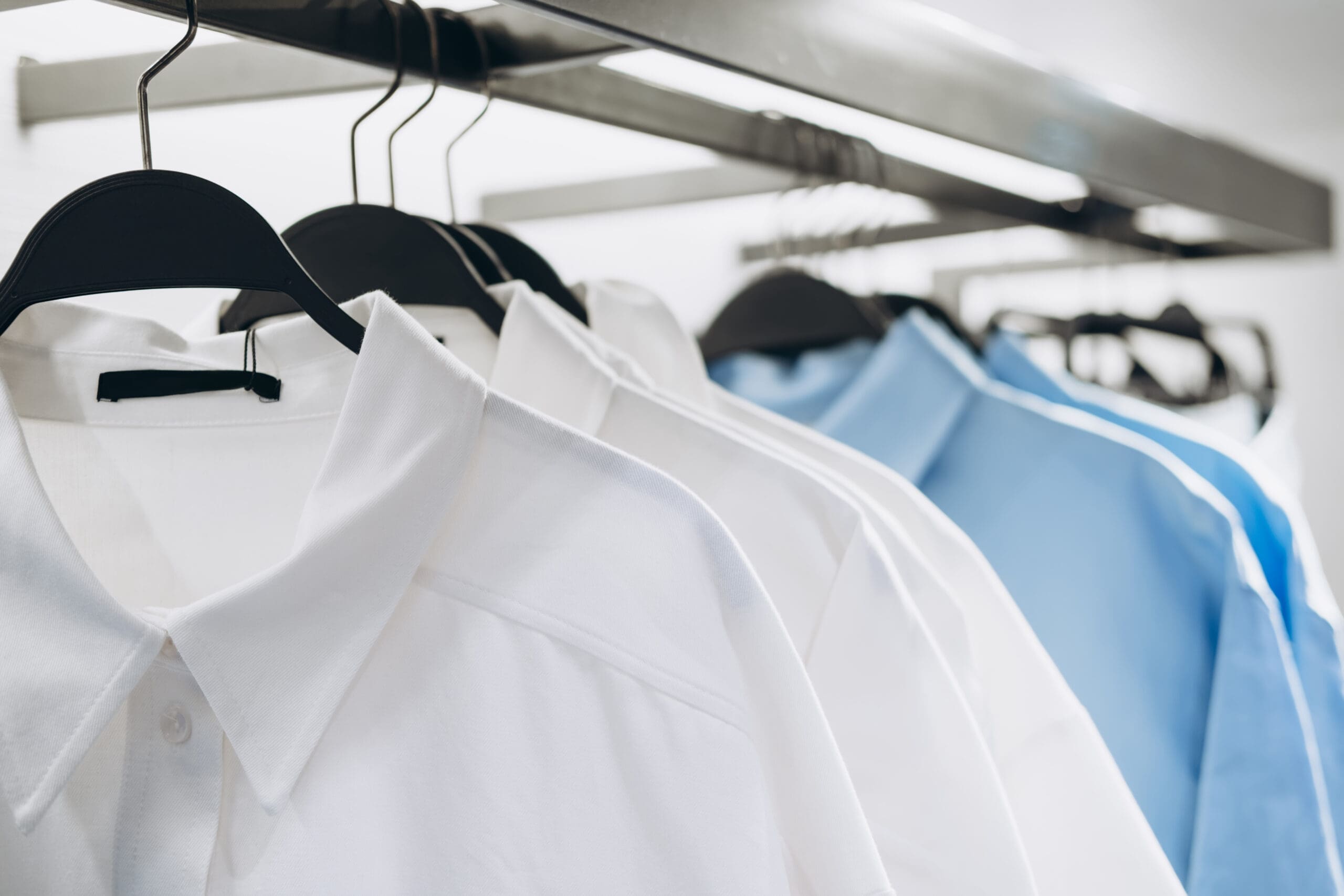 White and blue collared shirts hanging on a rack.